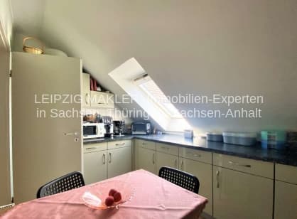 Dachgeschosszimmer mit Schrägdach, Küchenzeile, Esstisch und Dachfenstern