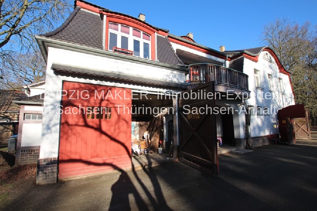 Zweistöckiges Wohnhaus mit weißer Fassade, roten Akzenten, Mansardendach und rotem Garagentor, Waldweg in Beucha