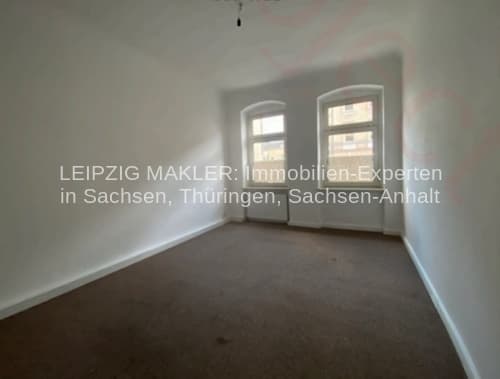 Leeres Zimmer mit Fensterfront, hellen Wänden und dunklem Bodenbelag