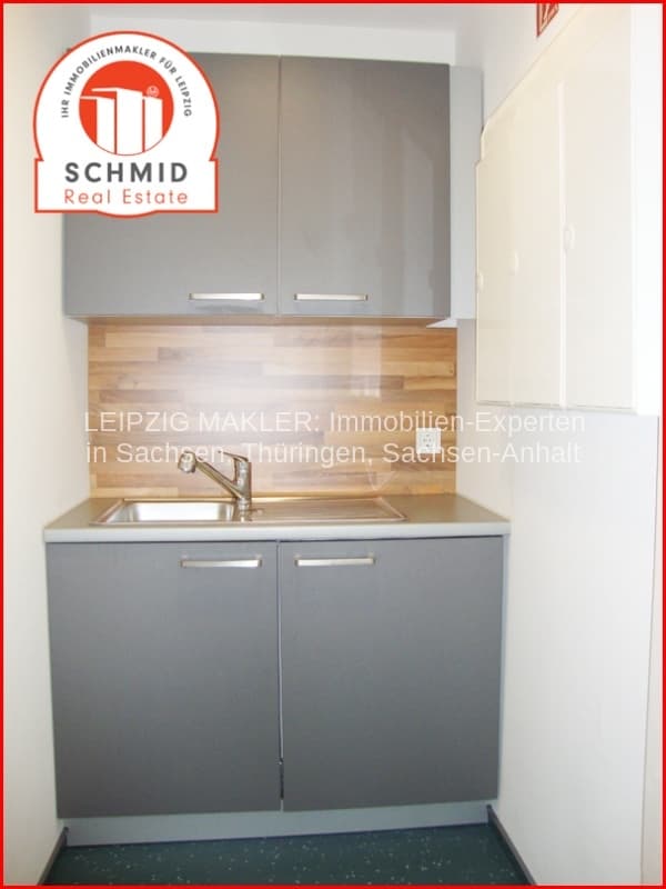Kleine Küchenzeile mit grauer Schrankfront, Spüle und Holzrückwand