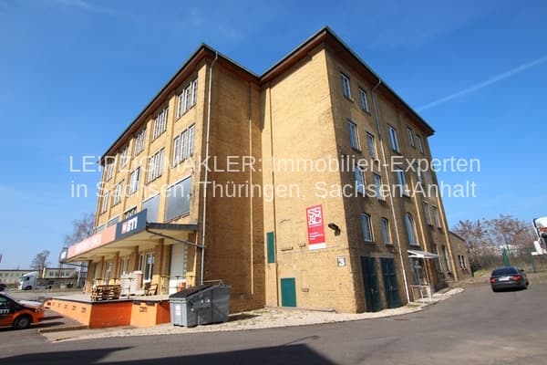 Vier-Geschoss-Gewerbegebäude mit Klinkerfassade, Satteldach, großflächiger Verglasung, Erdgeschoss-Ladenfront