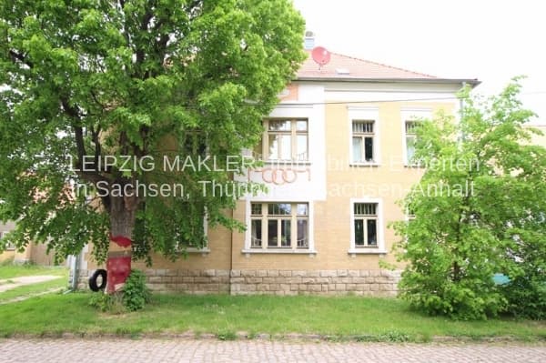 Zweigeschossiges Wohnhaus mit gelblicher Fassade, Satteldach und roten Ziegeln, von Bäumen umgeben, Lindenstraße in Lützen