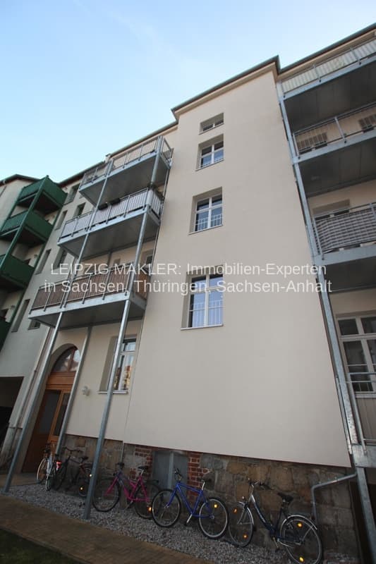 Fünfgeschossiges Wohnhaus mit beige verputzter Fassade, Metalllaubengänge auf der Seite, Fensterband, Erdgeschoss mit Sockel