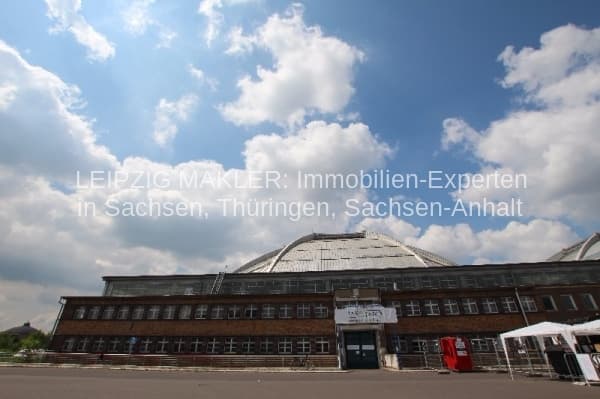 Backsteingebäude mit vier Geschossen und gewölbtem Glasdach, Fassade teilweise erneuert, großer Vorplatz