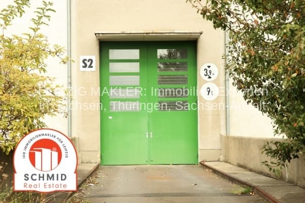 Grüne Eingangstür mit Oberlicht an cremefarbener Hausfassade, seitlich Efeu und Grünflächenbewuchs
