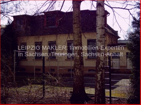 Zweistöckiges Wohngebäude mit Satteldach und Metallzaun, teilweise von Bäumen verdeckt, Schleußig in Leipzig
