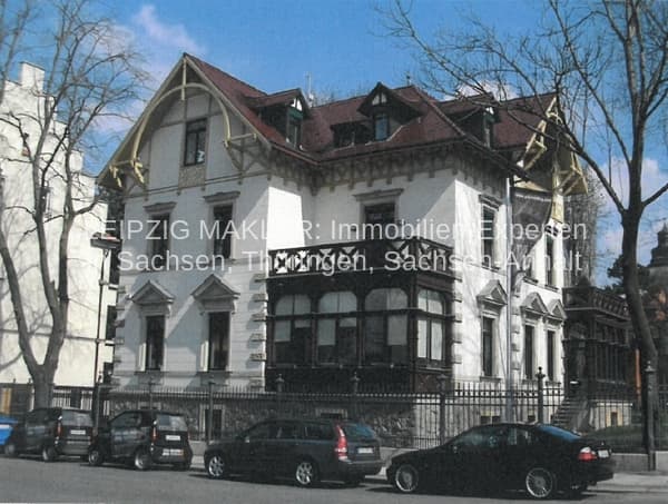 Zweigeschossige Gründerzeitvilla mit weißer Fassade, Mansarddach und Erkern, Straßenfront mit Metallgeländer, Laubbäume