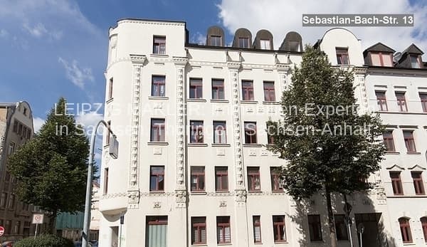 Vier- bis fünfgeschossiges Gründerzeithaus mit heller Fassade, Mansardendach und Efeu bewachsen