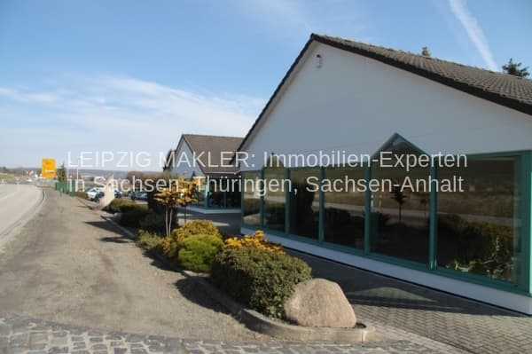 Eingeschossiges Gewerbegebäude mit weißer Fassade, großflächiger grüner Glasfront und Flachdach, B in Freyburg-Nißmitz