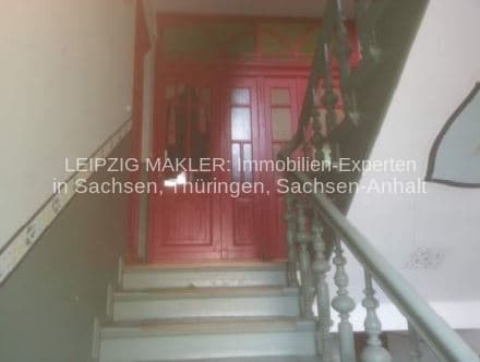 Treppenaufgang mit roten Innentüren und Geländer aus Holz