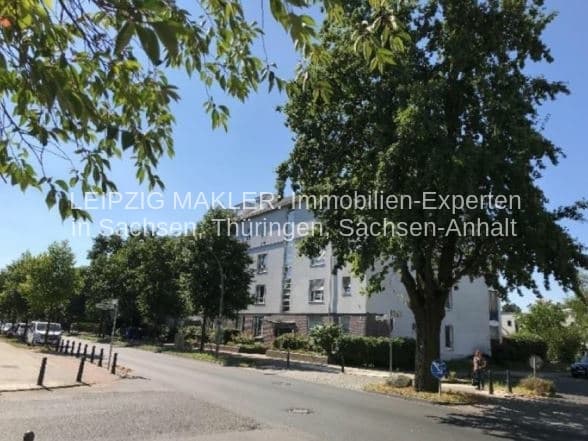 Mehrgeschossiges Wohngebäude mit heller Fassade, umgeben von hohen Bäumen, Blankenfelder Straße in Berlin