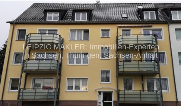 Viergeschossiges Wohnhaus mit gelber Fassade, Satteldach mit Gauben, drei Balkone, Frohburg