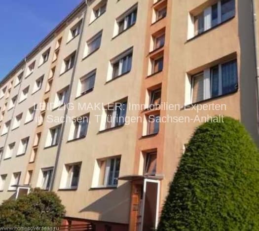 Fünfgeschossiges Wohnhaus mit beiger und orangefarbener Fassade, regelmäßigen Fensterreihen, Efeu an der Seitenwand, Frohburg