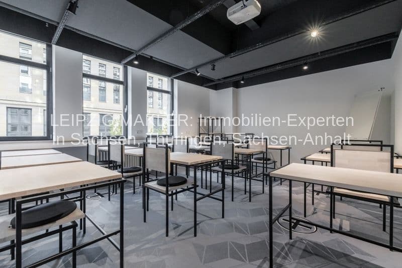 Großflächiges Büro mit schwarzer Decke, Holztischen, schwarzen Stühlen und großen Fenstern zur Peterstraße in Leipzig