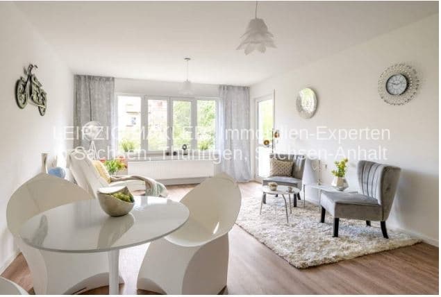 Helles Wohnzimmer mit Esstisch, Sitzgruppe, Parkettboden, großer Fensterfront und Wanddekoration