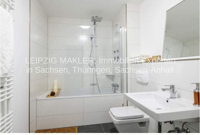 Badezimmer mit weißen Wandfliesen, Dusche mit Glaswand, Badewanne, Waschtisch und Spiegel