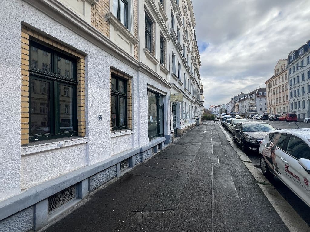 Mehrgeschossiges Gründerzeithaus mit weißer Fassade, grünen Fenstern und Ladenfront, Brandstraße in Leipzig-Connewitz