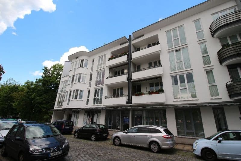 Viergeschossiges Wohngebäude mit weißer Fassade, Balkonen und Erdgeschossläden, Chopinstraße in Leipzig