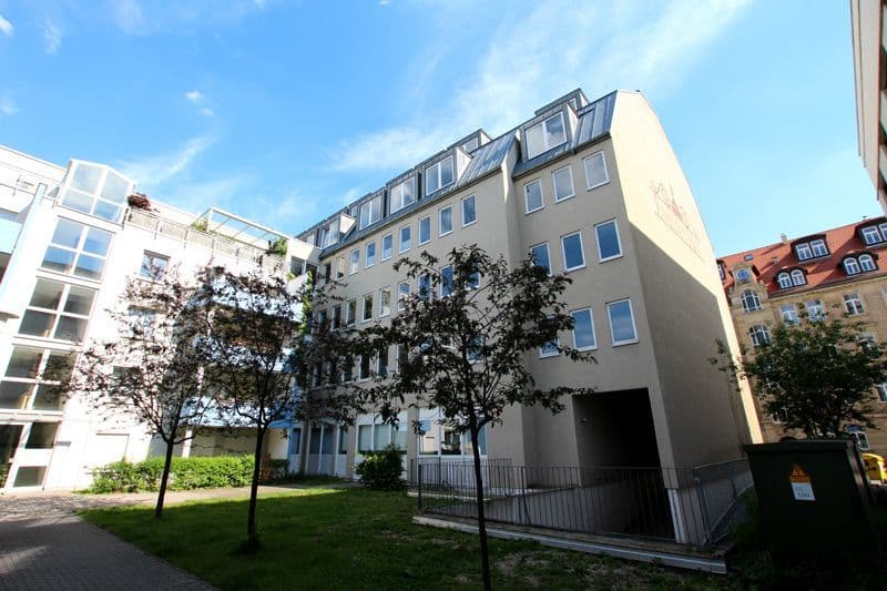 Fünfgeschossiges Wohngebäude mit Mansarddach, heller Fassade und regelmäßigen Fensterreihen, Emilienstraße in Leipzig