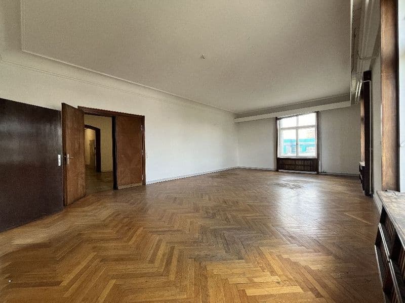 Leerer Raum mit Fischgrätmuster-Parkettboden, Holztüren, Fenster mit Heizkörper