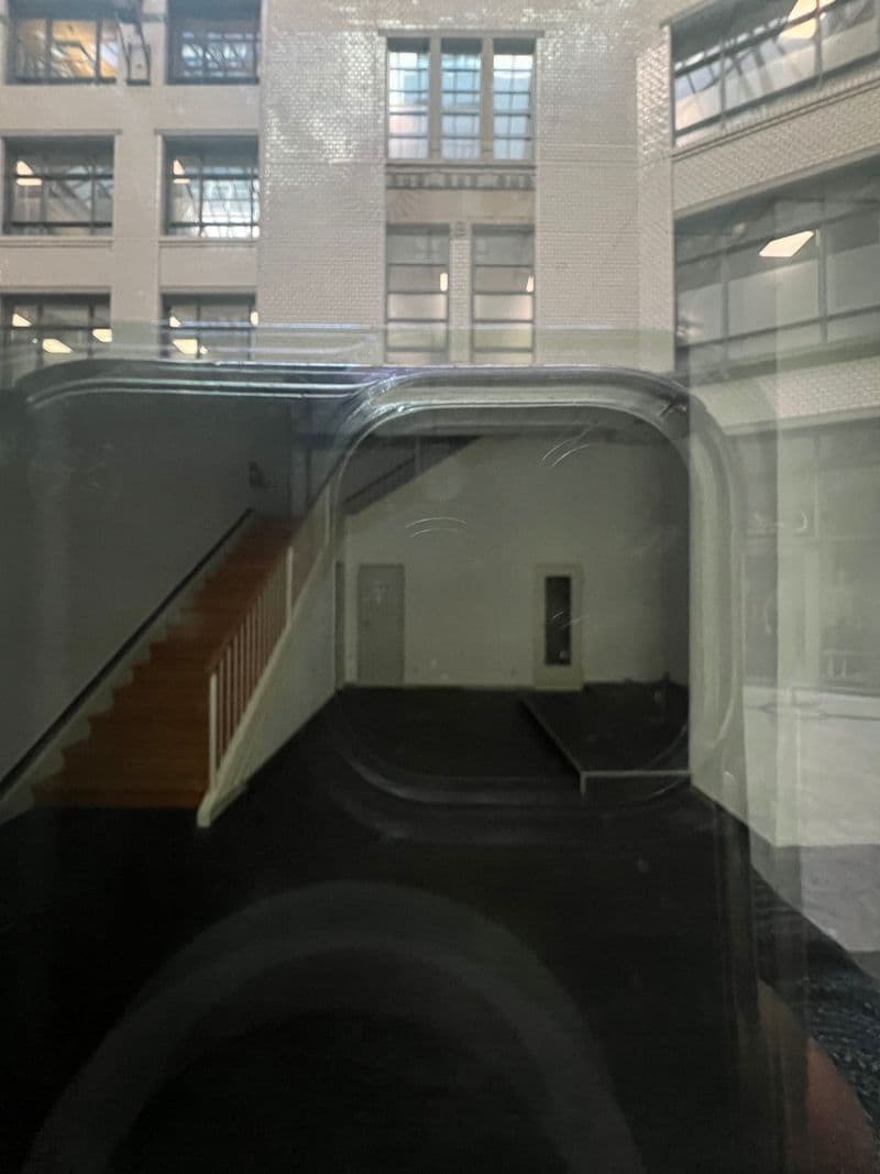 Einfahrt zu Tiefgarage mit gewölbter Decke, dahinter Innenhof mit Backsteingebäude und Glasgeländer