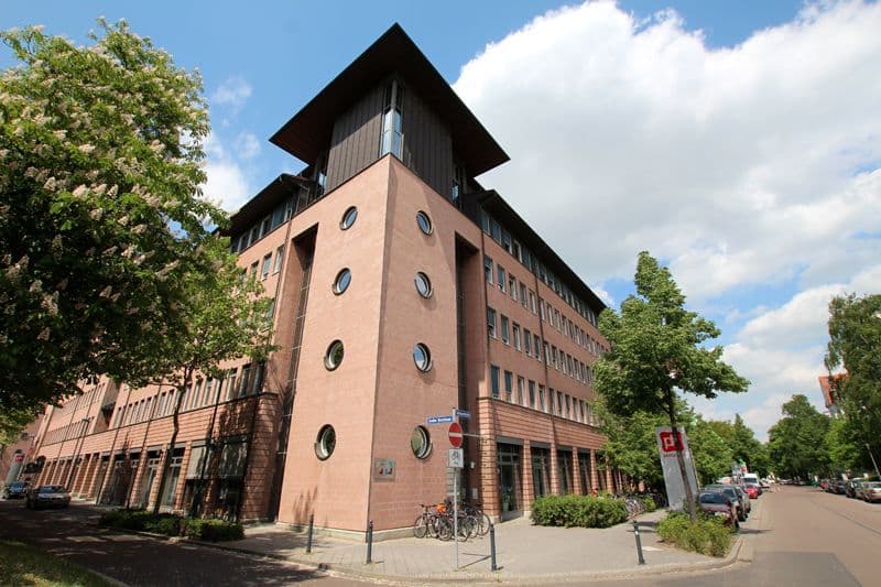 Fünfgeschossiges Backsteingebäude mit Turm, Rundfenstern an der Fassade und schwarzem Dach, Großer Brockhaus in Leipzig