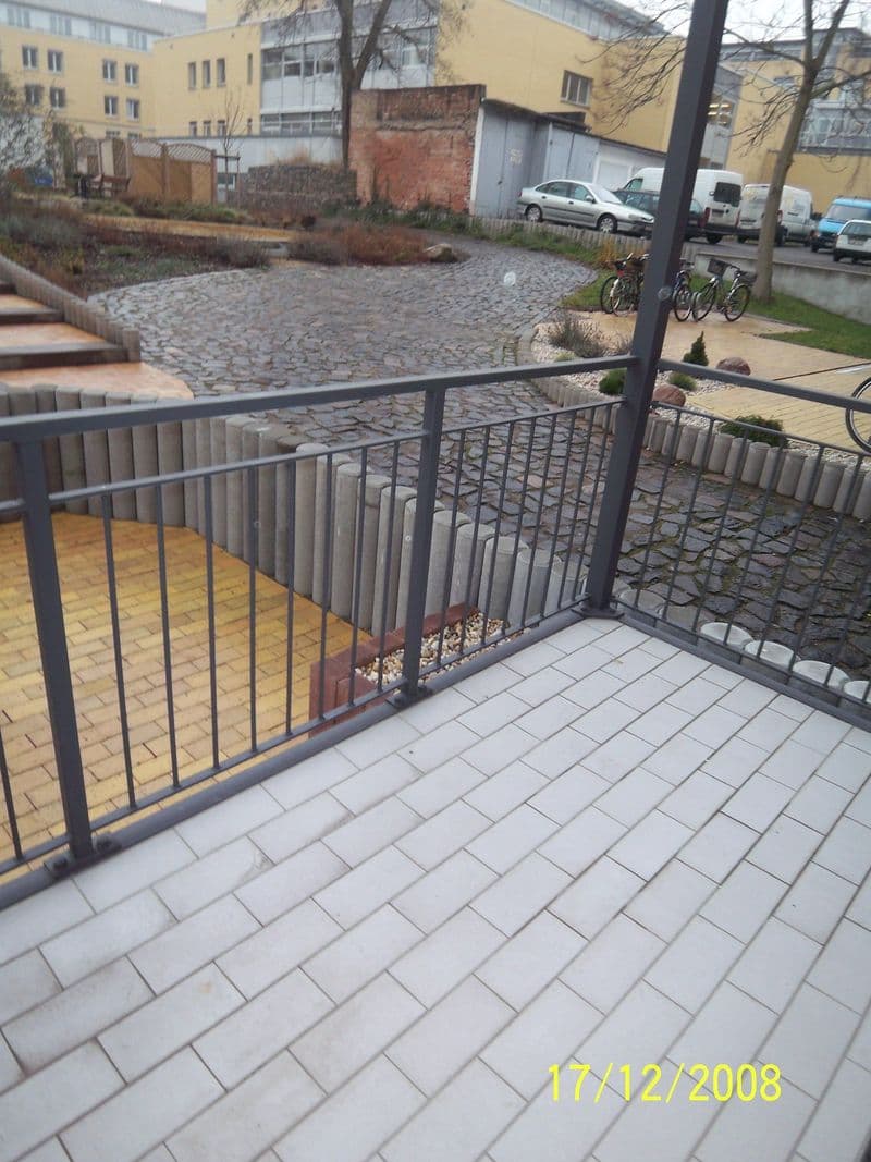 Terrassierte Außenfläche mit grauem Natursteinbelag, schwarzem Metallgeländer, Industriestraße in Leipzig-Plagwitz