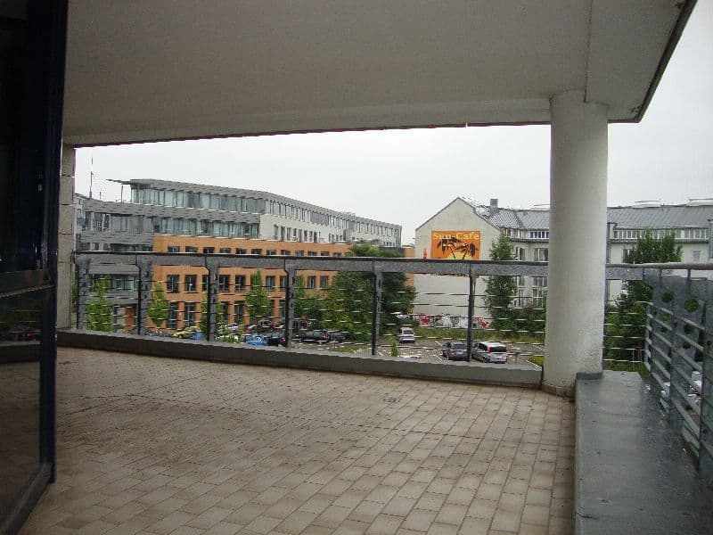 Balkon mit Betongeländer, Blick auf gelbes Geschäftsgebäude und mehrgeschossige Wohnhäuser, Ludwig-Erhard-Straße in Leipzig