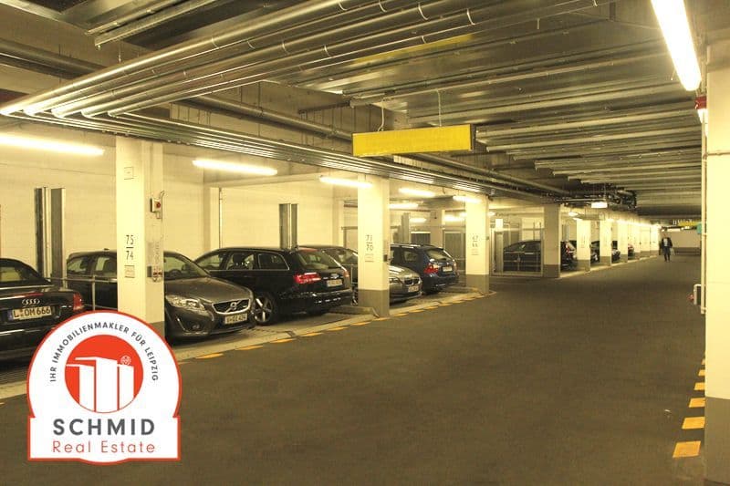 Tiefgarage mit Betonpfeilern, LED-Deckenleuchten, asphaltiertem Boden, markierten Parkplätzen und mehreren Autos