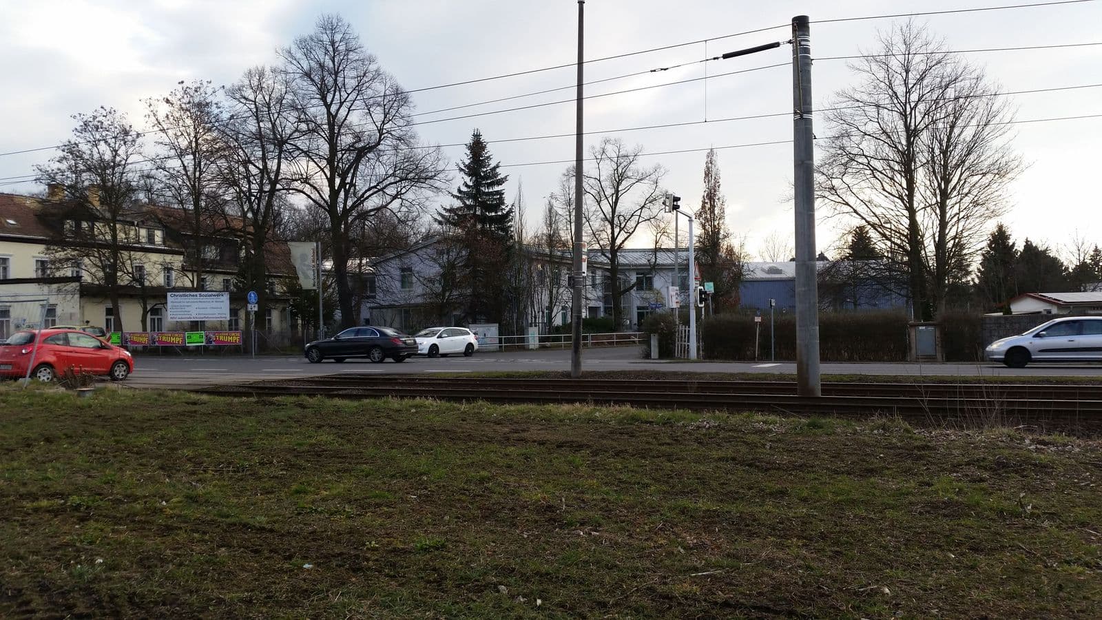 Straßenfront mit Straßenbahngleisen, zweigeschossigen Wohnhäusern links, Grünfläche vorne, Prager Straße in Leipzig