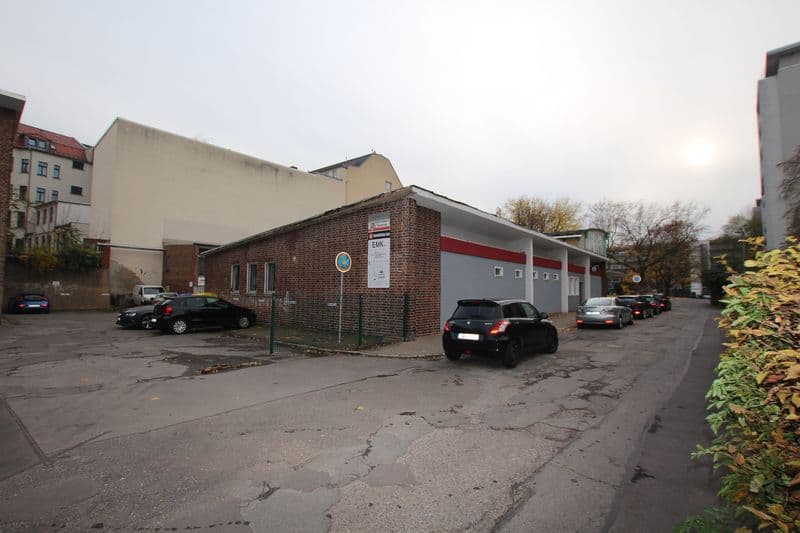 Eingeschossiges Backsteingebäude mit grauer Fassade und Garagentore, davor Parkplatz mit Autos, Waisenstraße in Chemnitz