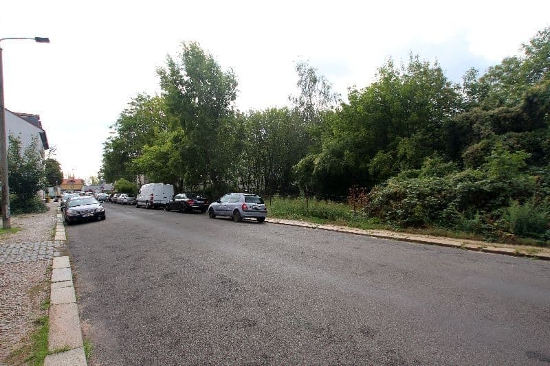 Asphaltierter Parkplatz mit mehreren Autos, links Wohngebäude, rechts dichter Baumbestand, Barbarastraße in Leipzig-Paunsdorf