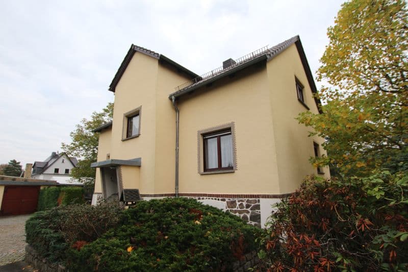 Zweistöckiges Einfamilienhaus mit cremegelber Fassade, dunklem Satteldach und Natursteinsockel, Leipziger Straße in Machern