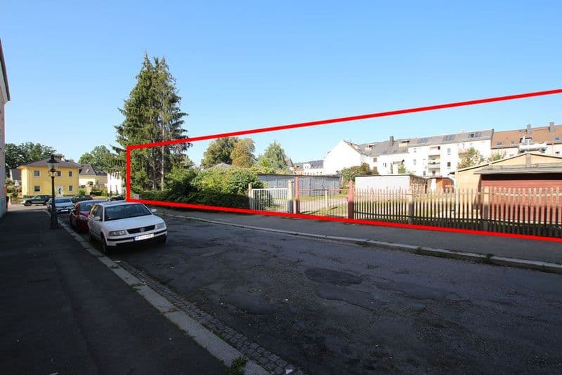 Parkplatz mit mehreren Autos, umgeben von Wohnhäusern unterschiedlicher Farben und Grünanlagen