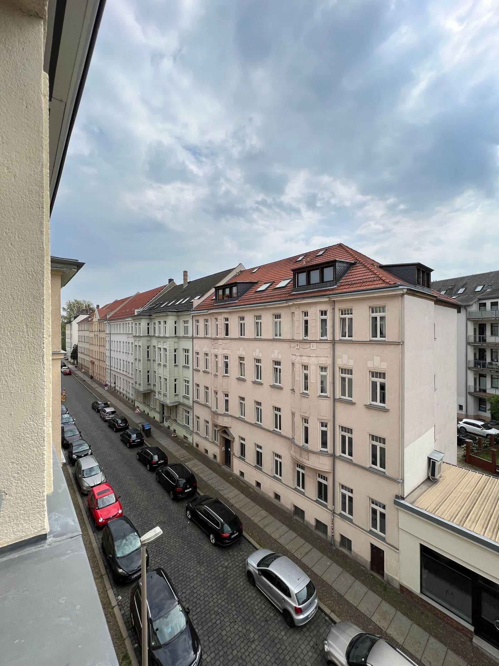 Mehrgeschossige Gründerzeitbauten mit Mansarddächern und roten Ziegeln, Fassaden verputzt, Seitenstraße mit geparkten Autos