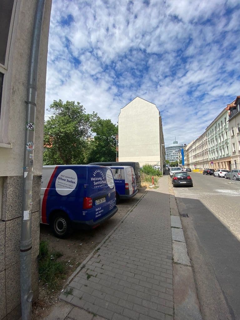 Straßenansicht mit mehrgeschossigen Wohnhäusern, Pflastersteinen und geparktem Handwerkswagen, Edlichstraße in Leipzig