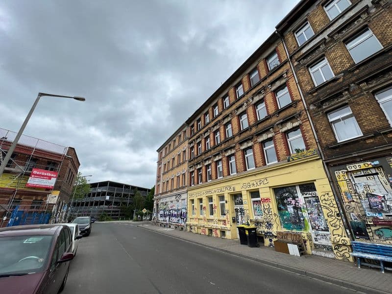 Fünfgeschossiges Backsteingebäude mit Rundbogenfenstern, Erdgeschoss mit gelber Fassade und Graffiti, Gießerstraße in Leipzig