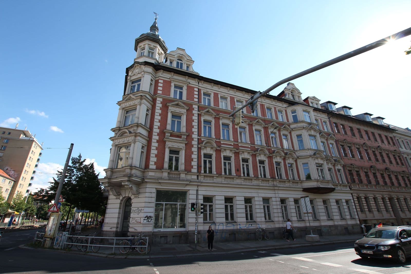 Fünfgeschossiges Gründerzeitgebäude mit roter Fassade, Mansardendach und Ecktürmen, Karl-Liebknecht-Straße in Leipzig