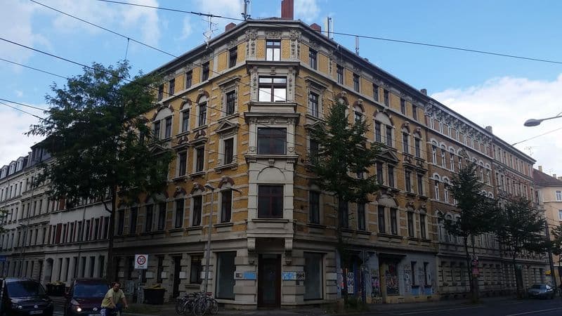 Fünfgeschossiges Gründerzeithaus mit gelber Fassade, Mansarddach und Straßenbäumen, Ludwigstraße in Leipzig-Volkmarsdorf