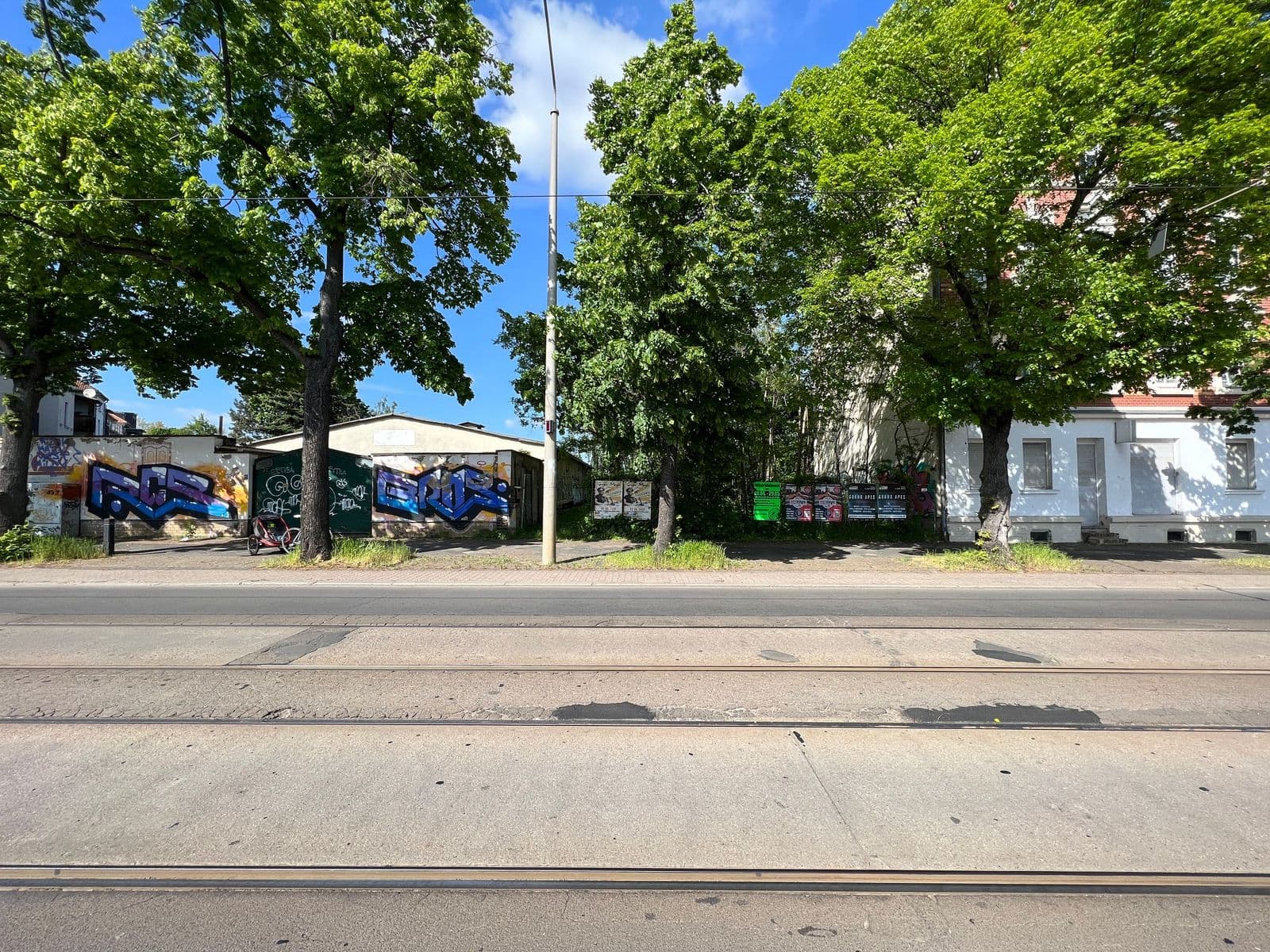 Straßenfront mit Bestandsgebäuden, Flachdächern und altem Baumbestand, Straßenbahngleise, Volbedingstr. in Leipzig-Mockau-Süd
