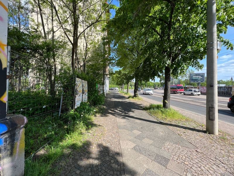 Baumbestandene Straße mit Gehweg aus Klinkern, Straßenbahn und Autos im Hintergrund, Volbedingstr. in Leipzig-Mockau-Süd