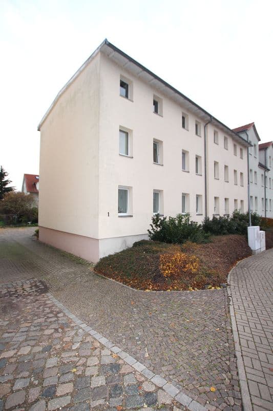 Dreigeschossiges Mehrfamilienhaus mit weißer Putzfassade, regelmäßig angeordneten Fenster in Wiesenstraße in Delitzsch