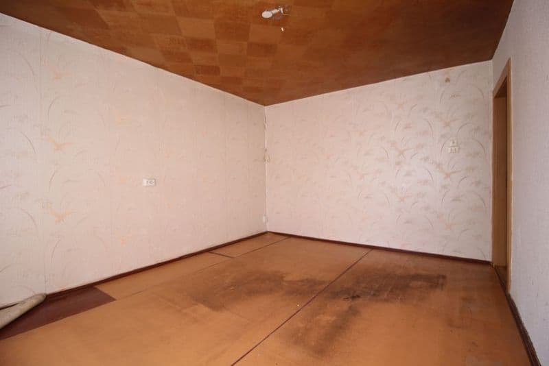 Leerer Raum mit Holzdecke in Schachbrettmuster, helles Tapetenmuster an den Wänden, Terrakottafliesenboden