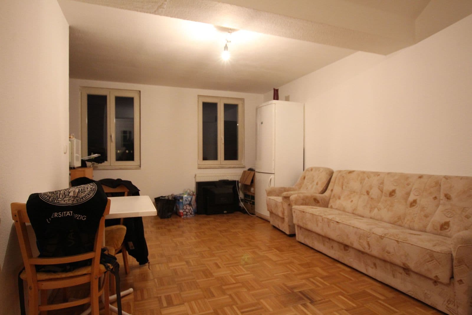 Wohnzimmer mit Parkettboden, Sofa, Essbereich, zwei Fenster und Kühlschrank, Blücherstraße in Leipzig