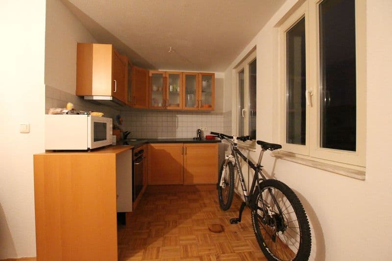 Küche mit Holzeinbauschränken, Fliesenspiegel, Fenster zur Balkontür, Parkettboden