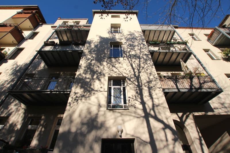 Fünfgeschossiges Wohnhaus mit heller Putzfassade, schwarzen Balkonen und Fensterrahmen, Cöthner Straße in Leipzig