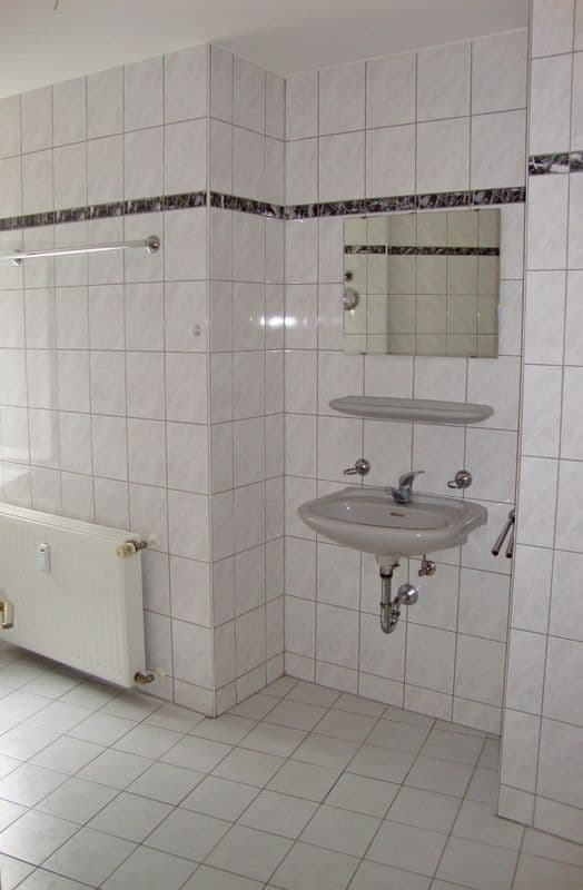 Badezimmer mit hellen Keramikfliesen, zwei Waschbecken, großem Spiegel und ebenerdiger Dusche mit Glastür