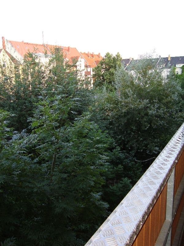 Blick von Balkon über dichte Begrünung auf mehrgeschossige Wohnhäuser mit Ziegeldächern, Dantestraße in Leipzig-Möckern