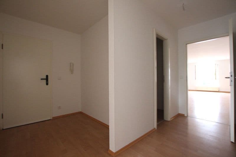 Flur mit Holzparkett, weiße Wände, mehrere Türen und offener Durchgang zu angrenzenden Räumen