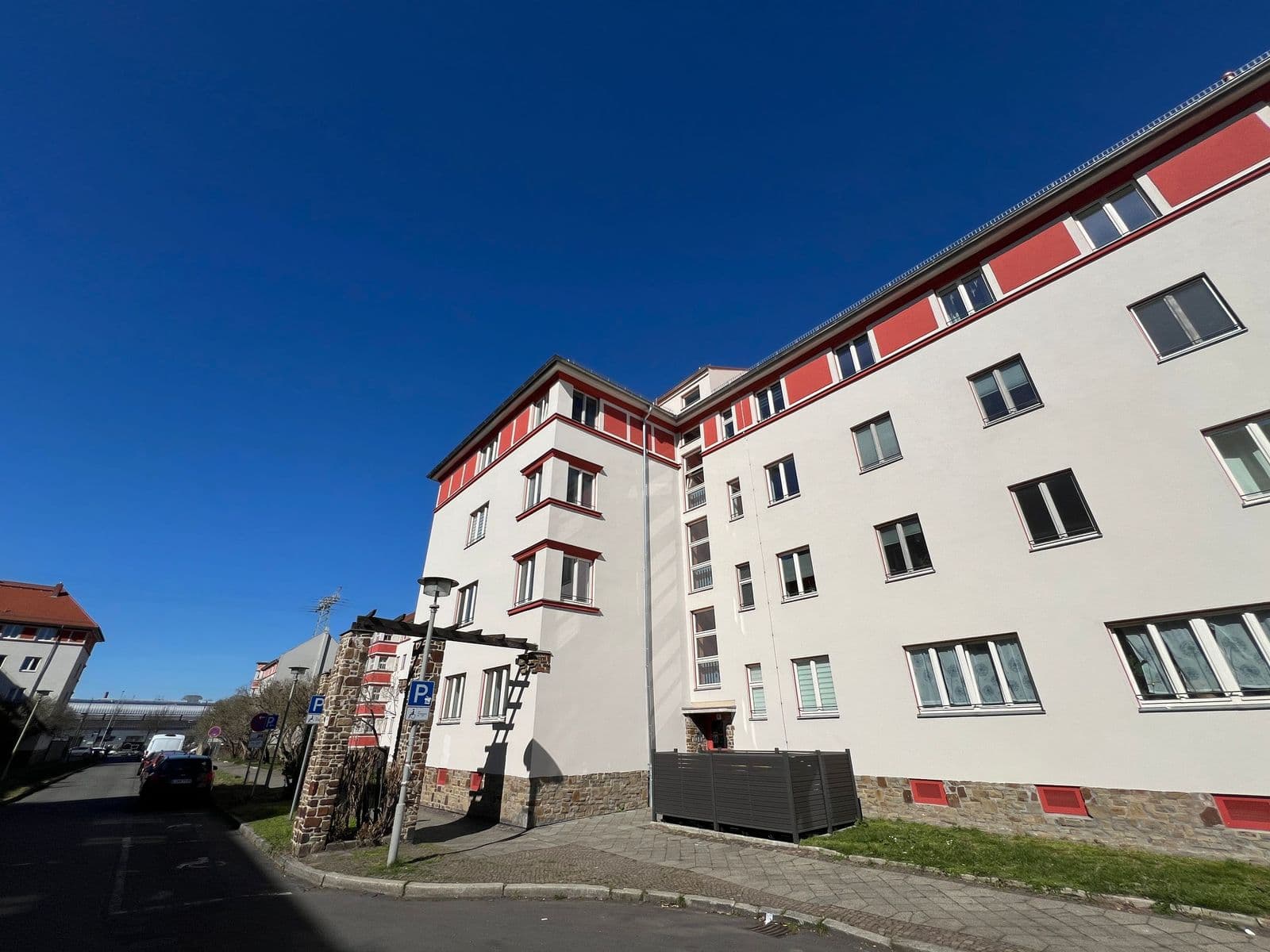 Mehrgeschossiger Wohnbau mit weißer Fassade, rote Dachkante und Balkone, Fliederhof in Leipzig-Schönefeld-Abtnaundorf